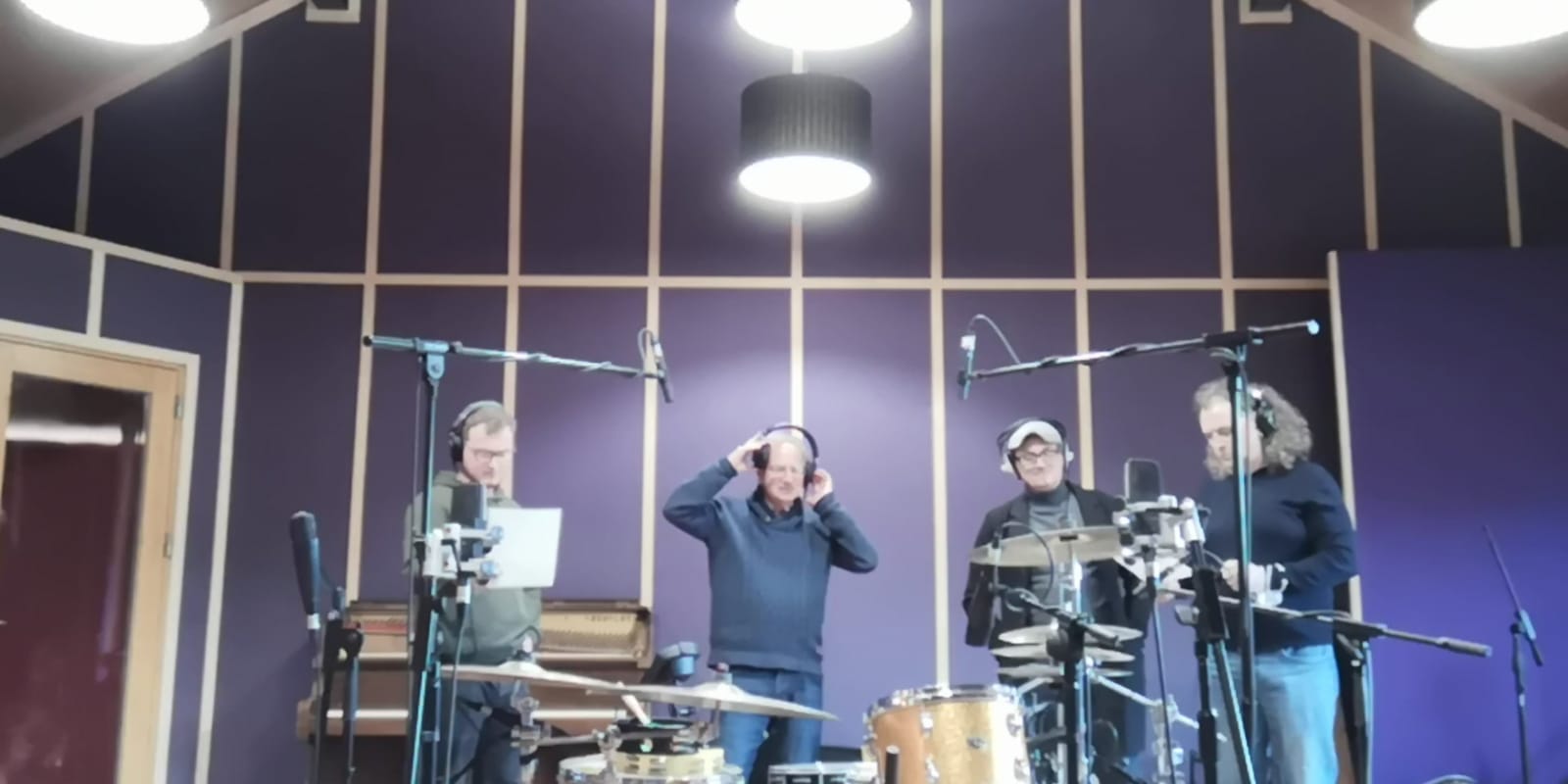 Photo of the recording studio, with Michael Weiss in the centre wearing
  headphones, flanked on the left by Sean Weiss staring intensly at a sheet of music, and on the right by Larry Hogan and
  Dazzey Oglesvey jamming along.